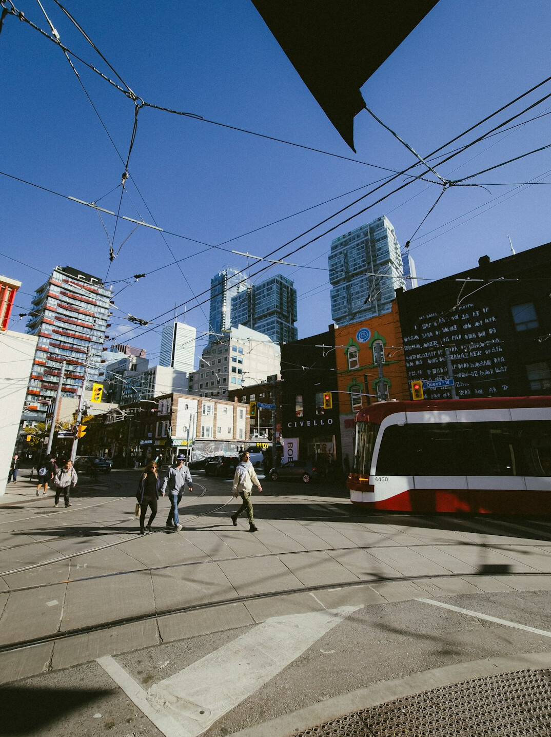 Pedestrians and streetcars crossing a busy downtown Canadian street
